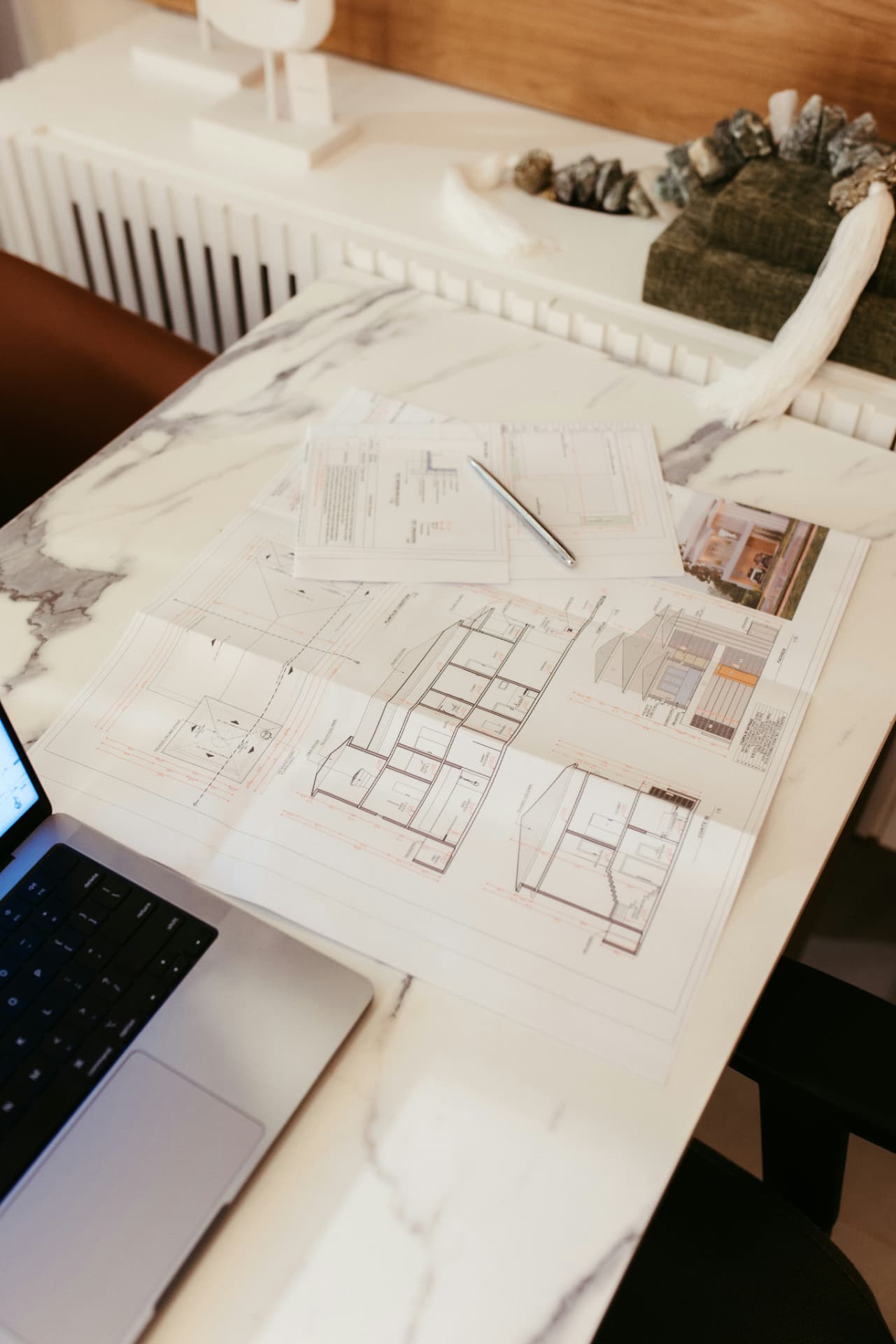 Bouwplannen en een lastenboek naast een laptop, klaar voor calculatie